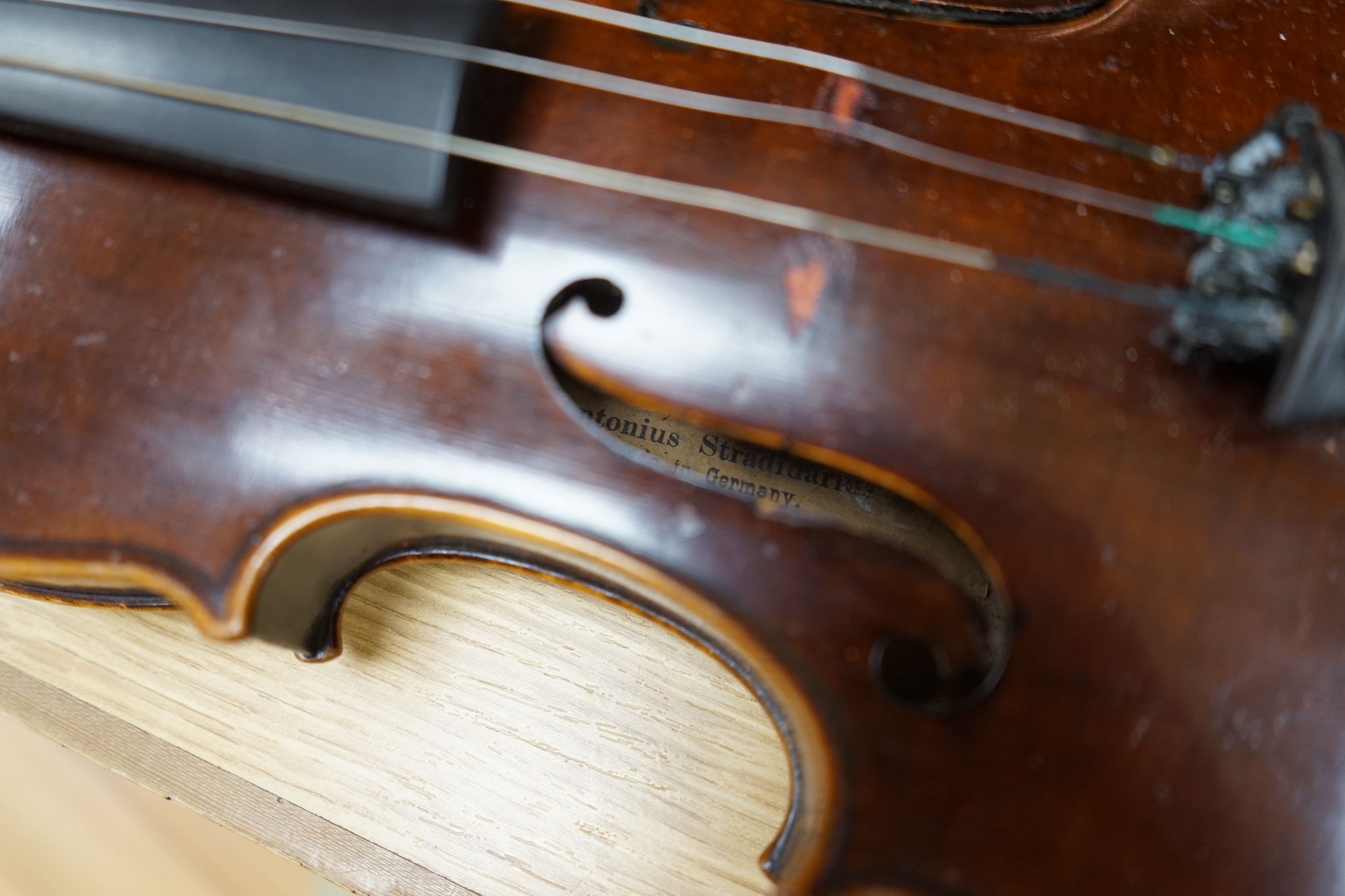 An early to mid 20th century violin, interior label reads ‘Copy of Antonius Straduarius made in Germany’, cased with bow, back measures 33.5cm. Condition - fair to good